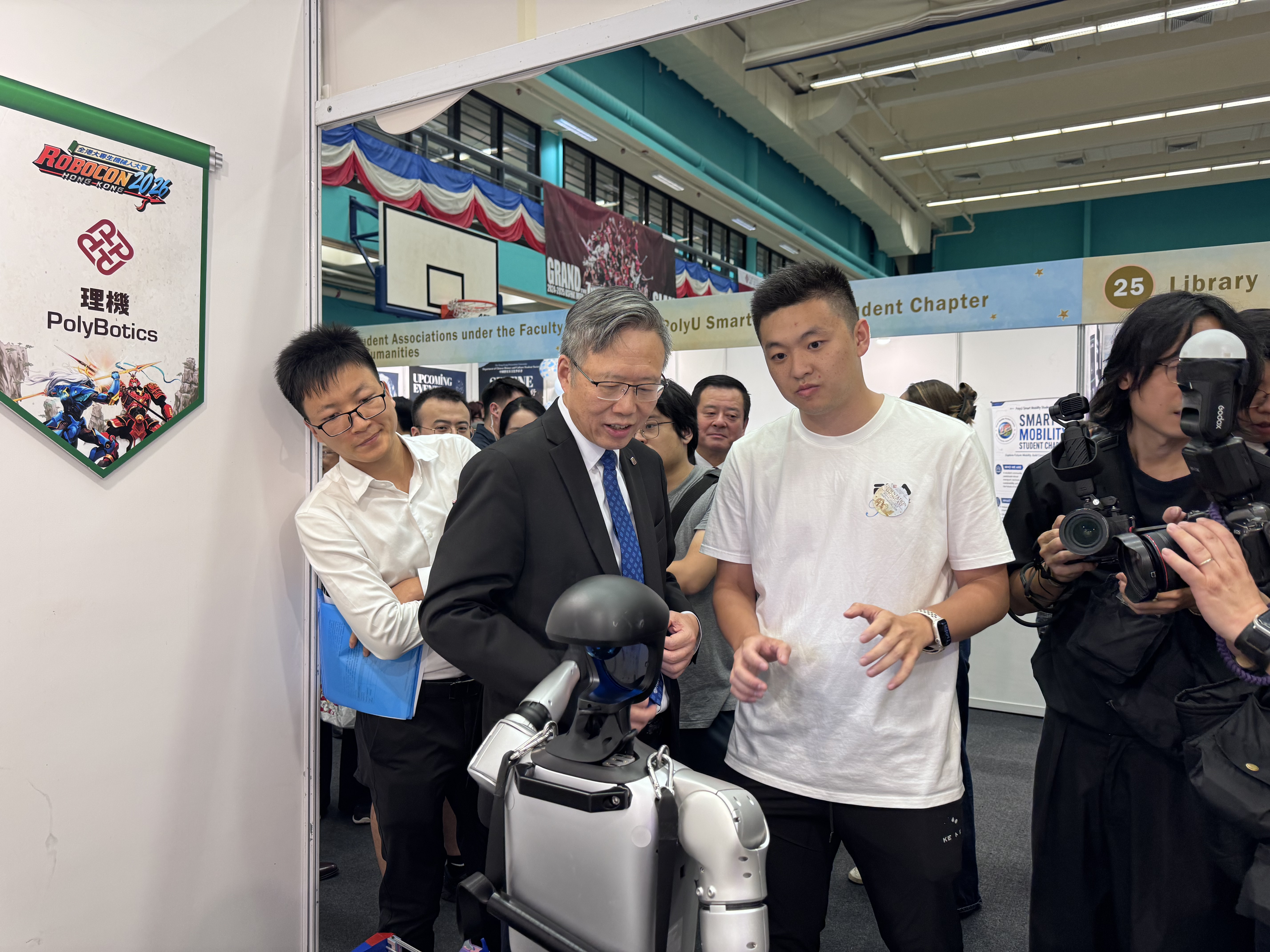 The President of PolyU viewing a humanoid robot at the PolyU FENG AI and Robotics Club booth